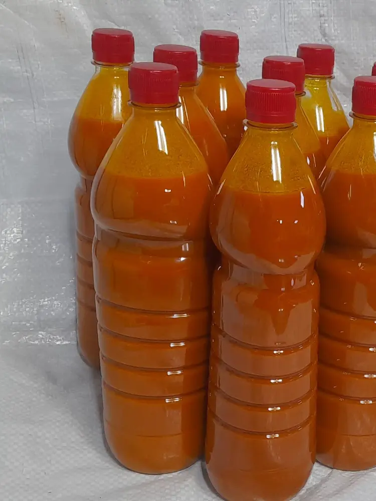 Row of bottles filled with bright orange palm oil, sealed with red caps